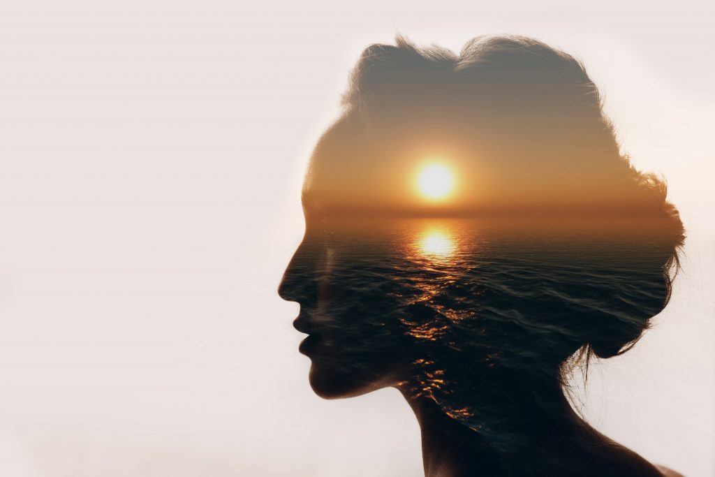 Silhouette of a woman's head with a sunrise image in her head illustrating mental health