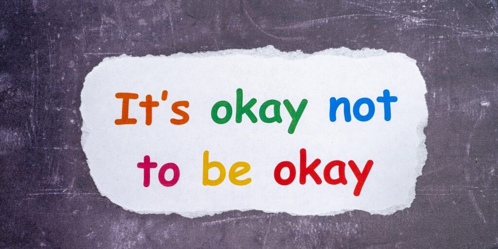 Mental  health and confidence issues with a text sign Its OK not to be OK printed on white paper and chalk board background