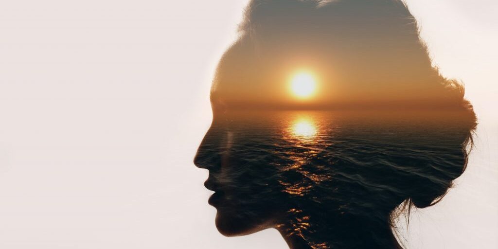 Silhouette of a woman's head with a sunrise image in her head illustrating mental health