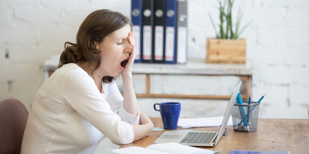 Shows a tired woman struggling to concentrate on work